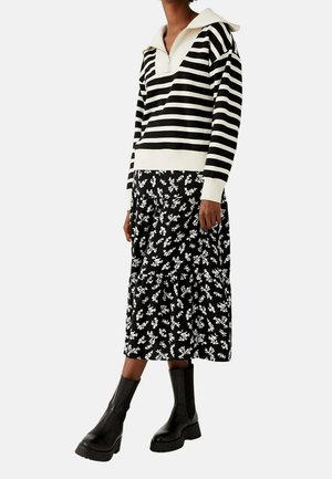 Sort og hvidstribet pullover med halv lynlås, parret med en lagdelt midi-nederdel i sort blomsterprint og sorte chunky ankelstøvler.