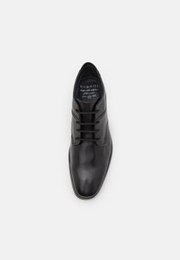 Zapato de vestir de cuero negro con un acabado liso, punta redonda y diseño de encaje con seis ojetes. Presenta costuras sutiles y una planta interior de marca.