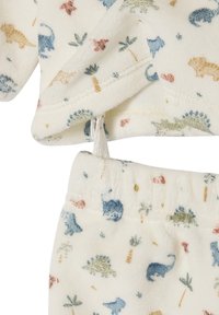 Fleece pajama set in cream with multicolored dinosaur and plant patterns. Features a pullover top and elastic waist pants with soft texture.