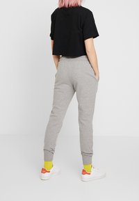 Black cropped t-shirt with short sleeves, paired with gray sweatpants featuring elastic waistband and cuffed ankles. White sneakers and bright socks.