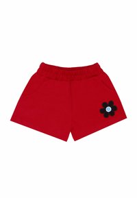 Pantalones cortos de algodón rojos con cintura elástica, que cuentan con dos bolsillos laterales y una aplicación de flor negra con un centro azul en la pierna izquierda.