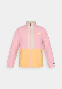 Chaqueta con cremallera para hombre, con la parte superior en color rosa, cuello y zona de cremallera beige, y sección inferior amarilla, que cuenta con bolsillos con cremallera y un pequeño emblema en el pecho.