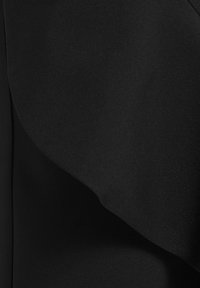 Zwart stof met een gladde textuur en een lichte glans. Bevat zachte plooien die een gedrapeerd effect creëren. Geen zichtbare patronen of hardware.