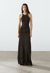 Abito lungo aderente nero con scollatura alta, realizzato in tessuto testurizzato, con una leggera lucentezza e una gonna fluida.