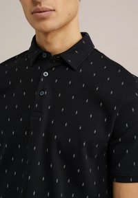 Polo negru cu un material texturat, având un model repetitiv de mici elemente albe. Placket cu trei nasturi și design cu guler.
