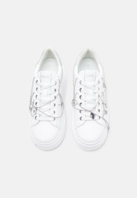 Białe trampki z gładkiej skóry, z srebrnymi metalowymi elementami i sznurowadłami w formie łańcuszka. Zaokrąglony czubek i miękkie, amortyzujące podeszwy.