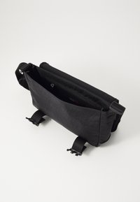 Borse a tracolla nera in materiale sintetico, con patta frontale, tasca con zip e tracolla regolabile. Caratterizzata da accessori durevoli e design minimalista.