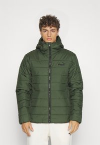 Giacca imbottita verde con cappuccio, dotata di zip frontale, cuciture orizzontali e un logo nero sul lato sinistro del petto. Texture liscia.