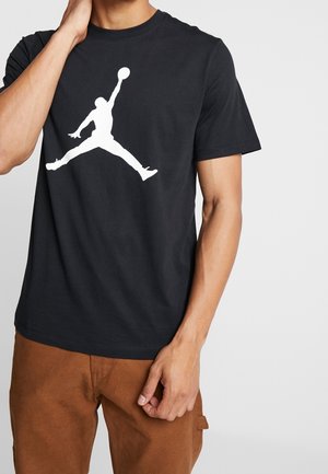 Sort T-shirt lavet af bomuld, med et stort hvidt Jumpman-logo i midten. Kortærmet og rund hals design.