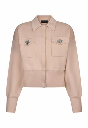 Giacca corta beige con maniche lunghe, due tasche frontali con pattina e decorazioni in cristallo su ogni pattina della tasca.