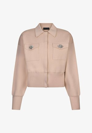 Bézs rövidített dzseki hosszú ujjakkal, két első zsebfedővel és kristály díszítéssel minden zsebfedőn.