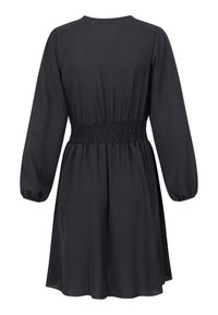 Vestido negro de corte relajado, con cintura fruncida, mangas largas y falda ligeramente acampanada. Fabricado con un tejido ligero de textura suave.