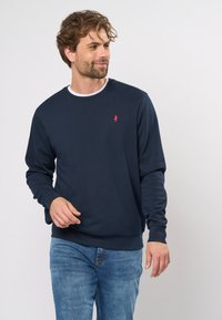 Hanorac bleu marin din bumbac, cu guler rotund și mâneci lungi. Prezintă un mic logo roșu pe piept.