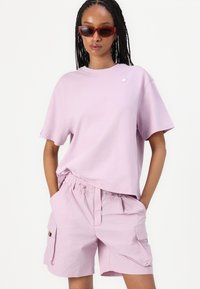 Hellscheinlila Baumwoll-T-Shirt mit kurzen Ärmeln, kombiniert mit passenden helllila Cargo-Shorts mit elastischem Bund und Seitentaschen.