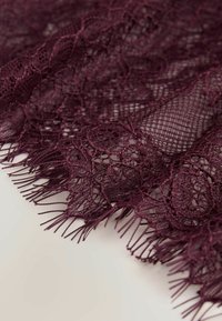 Burgundia pitskangas, mis sisaldab keerukaid lillemustreid ja tikandiga äärt, pehme tekstuuriga ning õrna avatud koega disainiga.