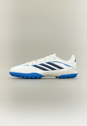 Λευκό και μπλε παπούτσι ποδοσφαίρου Adidas Copa με ναυτικές ρίγες και υφή μπλε σόλας, πλευρική όψη σε απλό μπεζ φόντο.