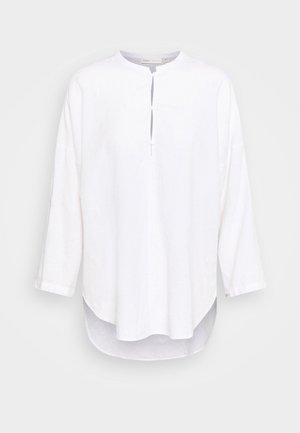 Weißes Leinenhemd mit rundem Ausschnitt, teilweisem Knopfleistenverschluss, Dreiviertelärmeln und einem leicht längeren hinteren Saum. Weicher Stoff.