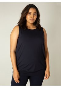 Marineblauwe mouwloze top van zachte stof met een relaxte pasvorm, ronde halslijn en een gelaagde zoom, ontworpen voor comfort en bewegingsvrijheid.