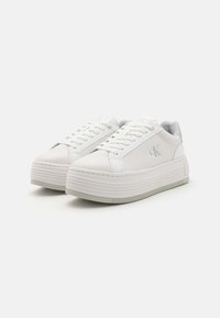 Vita plattformssneakers i texturerat läder, släta detaljer, platta snören och en grå logotyp. Har en räfflad yttersula för bra grepp.