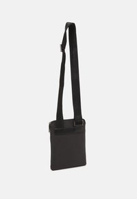Borsa a tracolla nera con forma rettangolare. Realizzata in tessuto liscio con una tracolla strutturata. Presenta una chiusura con zip e una tasca anteriore piatta.