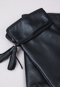 Black leather clutch bag with a textured finish, featuring a top flap and decorative tassels attached to the closure.