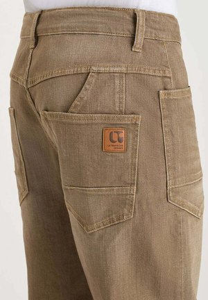 Bruine werkbroek met versterkte dubbele achterzakken en een leren label op de naad van de rechterzak.