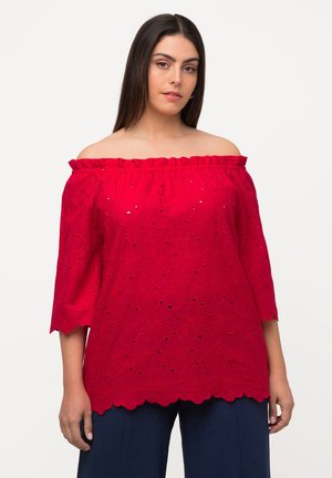 Blusa rossa off-the-shoulder con scollo arricciato, maniche a ¾, motivo floreale a taglio e orlo scallopato. Realizzata in tessuto leggero.