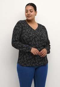 Haut noir à manches longues avec un décolleté en V, orné d'un motif floral violet et vert, fabriqué dans un tissu léger.