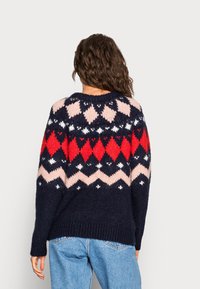 Pull en maille bleu marine avec un motif géométrique coloré en rouge, rose et blanc. Présente un col rond et une coupe décontractée.