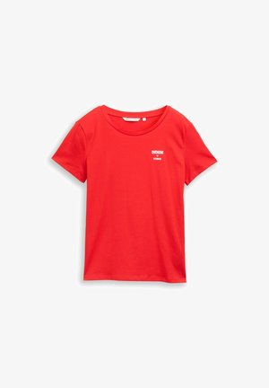 Červené bavlnené tričko s okrúhlym výstrihom a krátkymi rukávmi. Na hrudi má biele nápisy "DENIM" a "STUDIO". Hladká textúra.