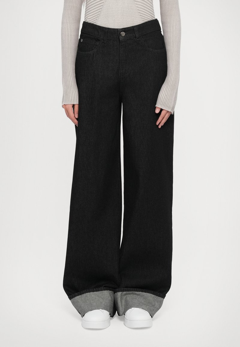 Black wide-leg denim jeans with a high waist, featuring two front pockets and folded gray cuffs, paired with white sneakers.