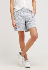 Jasnoniebieskie szorty w wzór diamentów, wyposażone w elastyczny pas. Połączone z białymi trampkami i zapinaną na guziki białą koszulą.