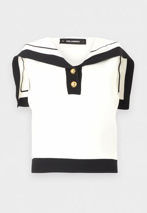Witte gebreide top met zwarte biezen, zeemanskraag, twee gouden knopen op de voorbies en contrasterende zwarte zoom- en mouwranden.