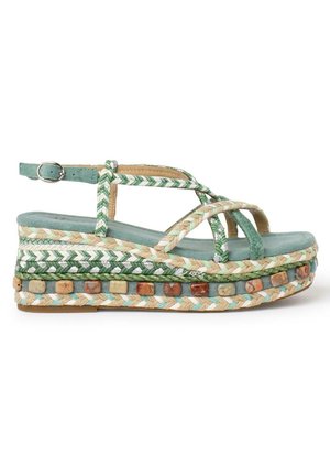 Sandale plateforme avec semelle confortable en daim vert, brides tressées vertes et beiges, boucle à la cheville, et détail en pierres multicolores autour du bord de la semelle.