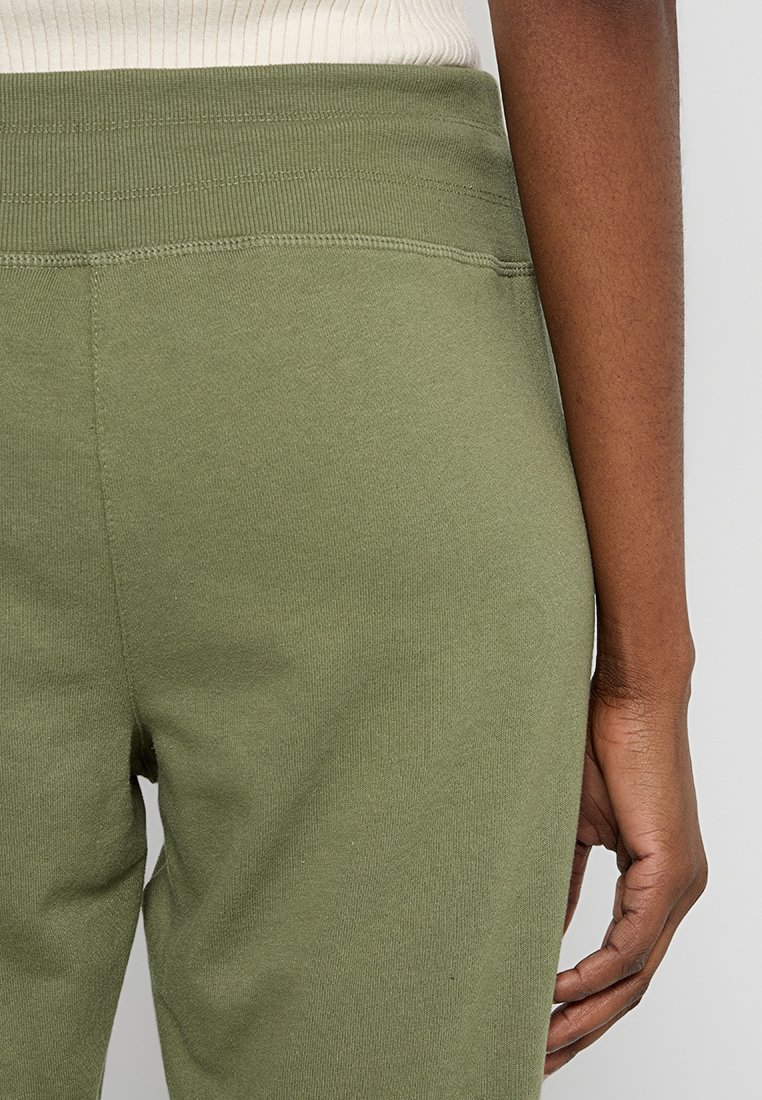 Pantaloni jogger verde oliva con una vita elastica rigata, realizzati in morbido cotone e con un design aderente. Dettagli di cucitura evidenti alla vita.