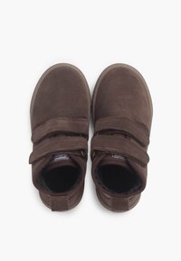 Botas de ante marrón con dos correas de Velcro, punteras redondeadas y suelas de goma. Forro interior suave y acabado texturizado.