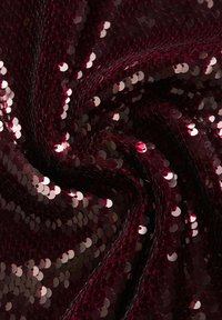 Tissu en sequins bordeaux à texture lisse, présentant des sequins circulaires réfléchissants qui créent une surface scintillante.