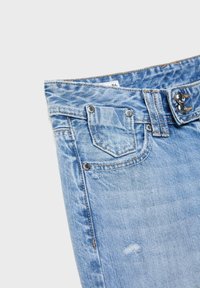 Hellblaue Jeans mit Taillenbund, vorderer Tasche, Gürtelschlaufen, Metallnieten und doppelter Knopfverschluss.