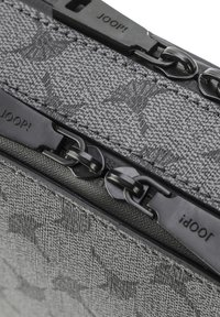 Borsetta grigia con zip realizzata in tessuto, caratterizzata da un motivo testurizzato, con componenti neri e il nome del marchio "JOOP!" impresso sui tiranti della zip.