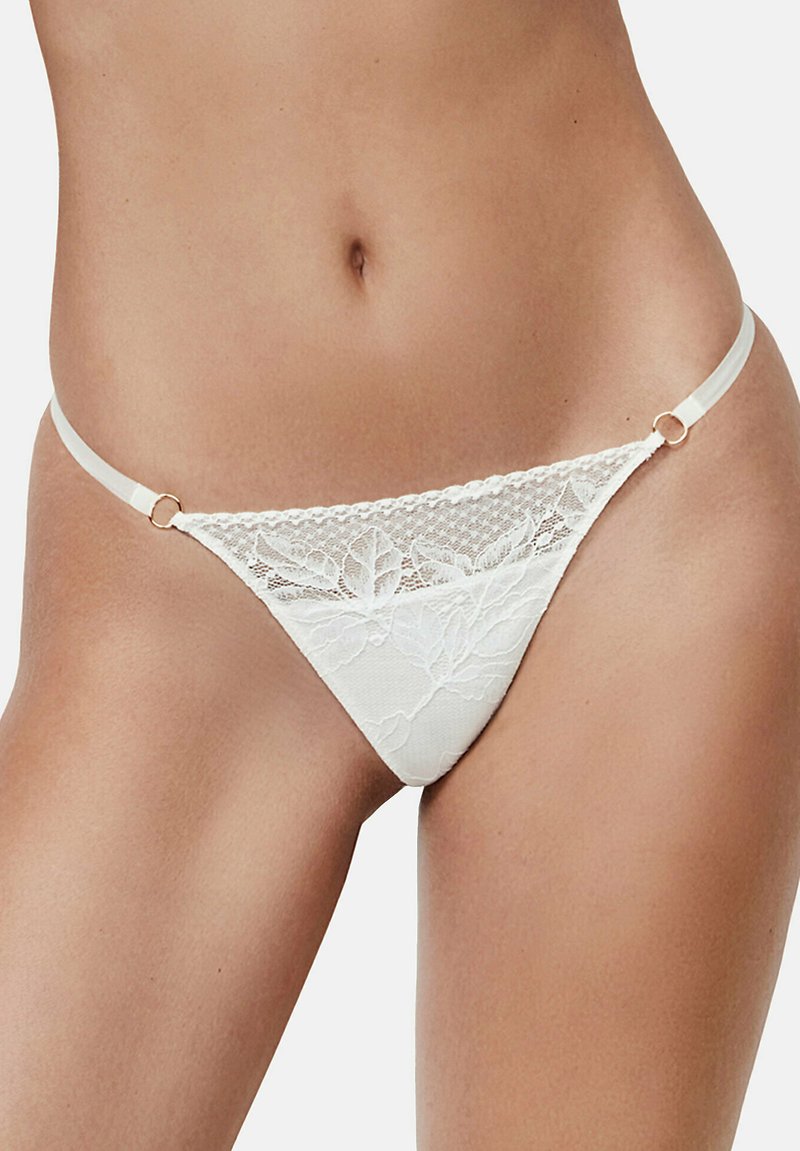 Kant string in crème kleur met bloemenpatroon, doorzichtige bovenkant en dunne zijkanten met gouden hardware accenten.
