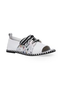 Witte geperforeerde leren schoen met een open teen, voorzien van zwarte veters, kleurrijke bloemenaccenten en een gestreepte zwart-witte zool.