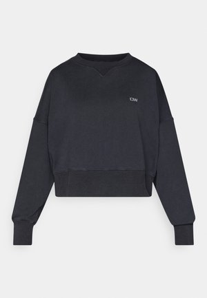 Sweat-shirt court noir à manches longues. Présente des poignets et un ourlet côtelés, un col rond, et un petit logo sur la poitrine. Texture douce.