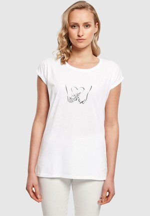 Hvid t-shirt med korte ærmer, der viser en sort linjetegning af to hænder, der danner en hjerteform med ordet "kærlighed" indeni.