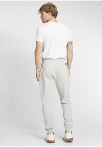 Lätta gråa sweatpants med en tapered form och sidosträck, matchade med en enkel vit t-shirt och ljusa sneakers. Enkelt design, avslappnad passform.