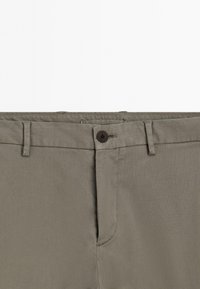 Grijze casual broeken met een knoopsluiting in de taille, riemlussen en een gedeeltelijk zichtbare flap.