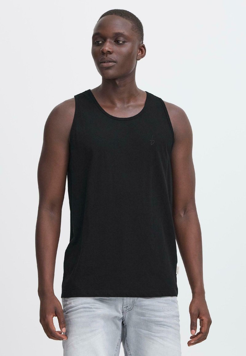 Svart bomullstopp med rund halsringning, utstyrt med en subtil logo på brystet. Tøyet virker glatt og lett.