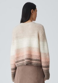 Texturiertes, gestricktes Sweatshirt mit einem Farbverlauf von Creme, hellrosa und braunen Farbtönen, in cropped Design und mit gerippten Akzenten.