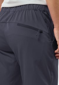 Dunkelgraue Sporthose mit elastischem Bund, ausgestattet mit einer Reißverschlusstasche und einem glatten, leichten Stoff für angenehmen Tragekomfort.