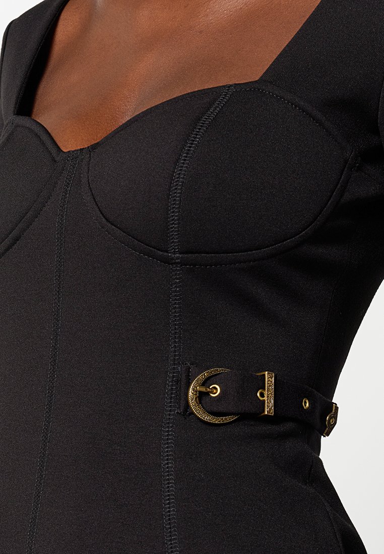 Zwart aansluitend jurkje met een gestructureerd lijfje, met naaddetails en een gouden gespaccent op een zijband. Gladde textuur van de stof.