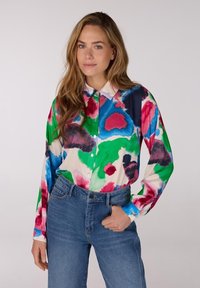 Multikleurig overhemd met lange mouwen en knoopsluiting, met een abstract bloemenpatroon in blauw, groen, roze en rood op een crèmekleurige achtergrond.